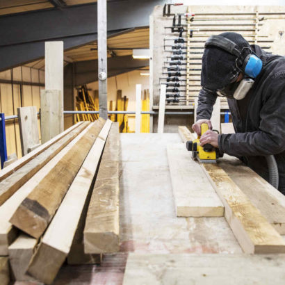 mężczyzna używający szlifierki taśmowej do szlifowania desek