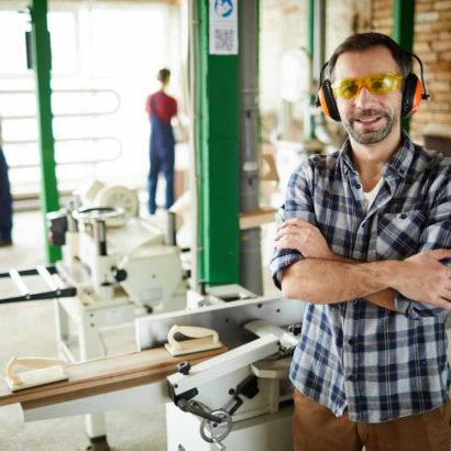 mężczyzna pracujący w przemyśle ma w swoim zakładzie przecinarki tarczowe i przecinarki taśmowe, narzędzia przydatne w przemyśle