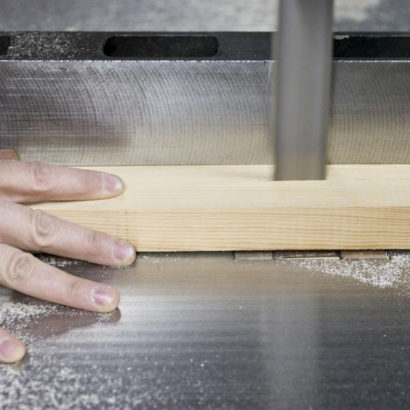 mężczyzna tnący drewno za pomocą piły taśmowej do drewna